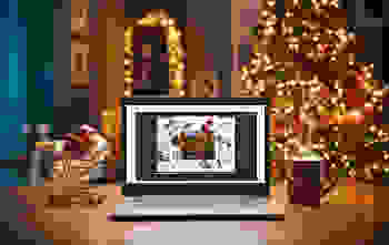 Laptop on a desk showing a holiday catalog, with a Christmas tree in the background